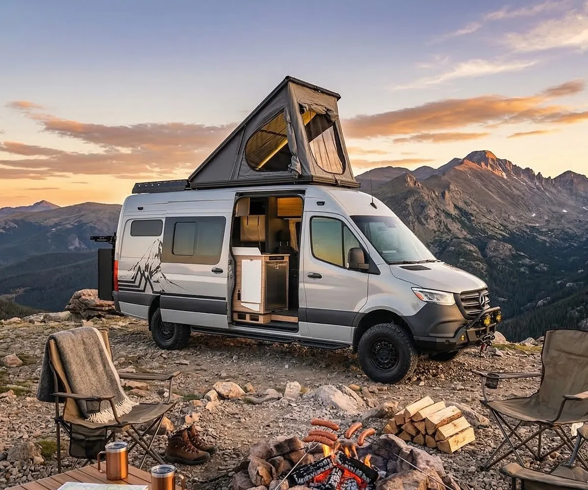 The Parbat at a mountain camp at sunset, its rooftop tent open and a fire lit in the foreground