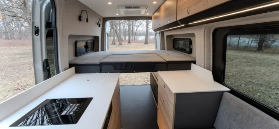Aoraki galley counter with sink and induction cooktop, rear doors open to a field