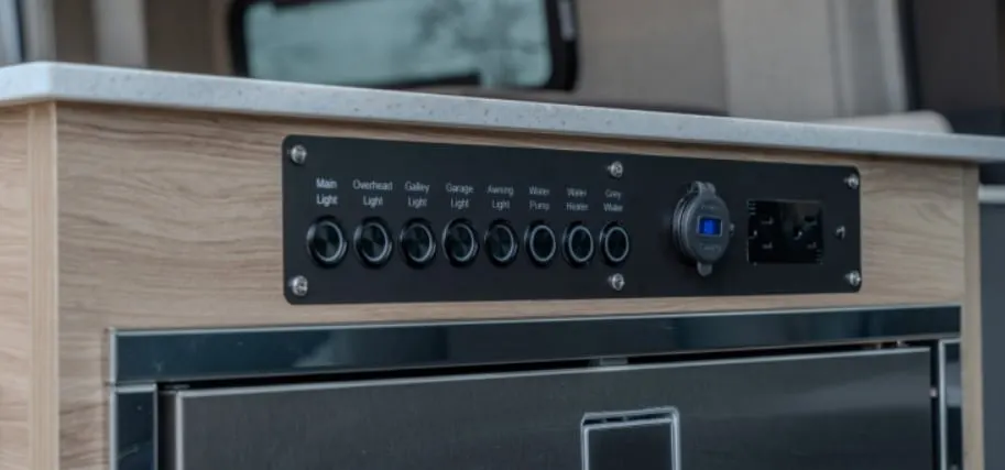 Twelve-volt switch panel and shore power inlet set into the galley cabinet