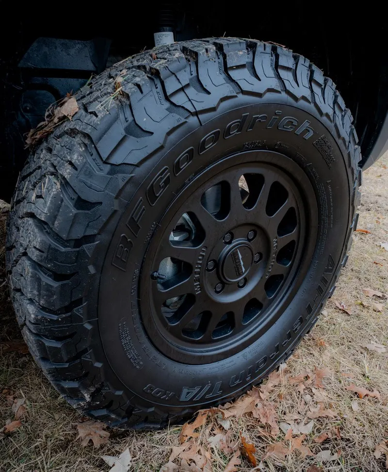 A BFGoodrich All-Terrain T/A KO3 tyre on a black Method wheel, parked on leaf litter