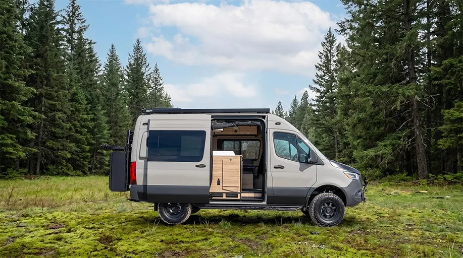 The same AORAKI in a forest clearing, sliding door open on the galley and the rear storage box swung out