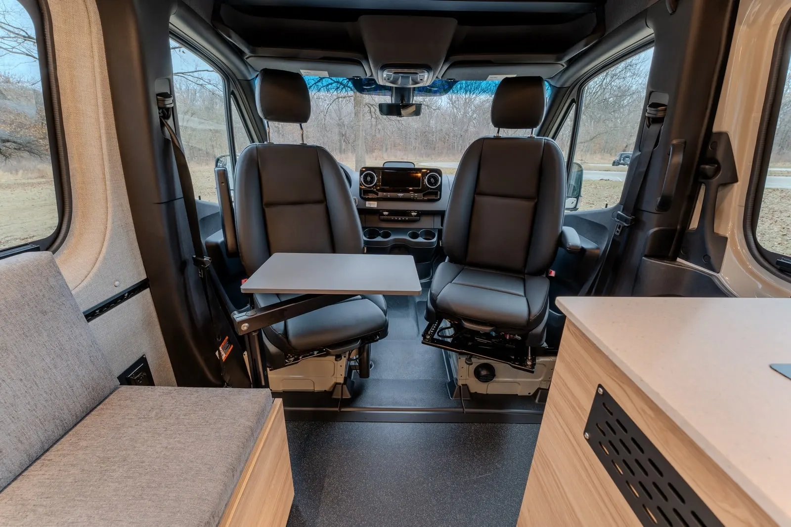 Aoraki cabin looking forward: two swivelled cab seats, a table between them and wood cabinetry