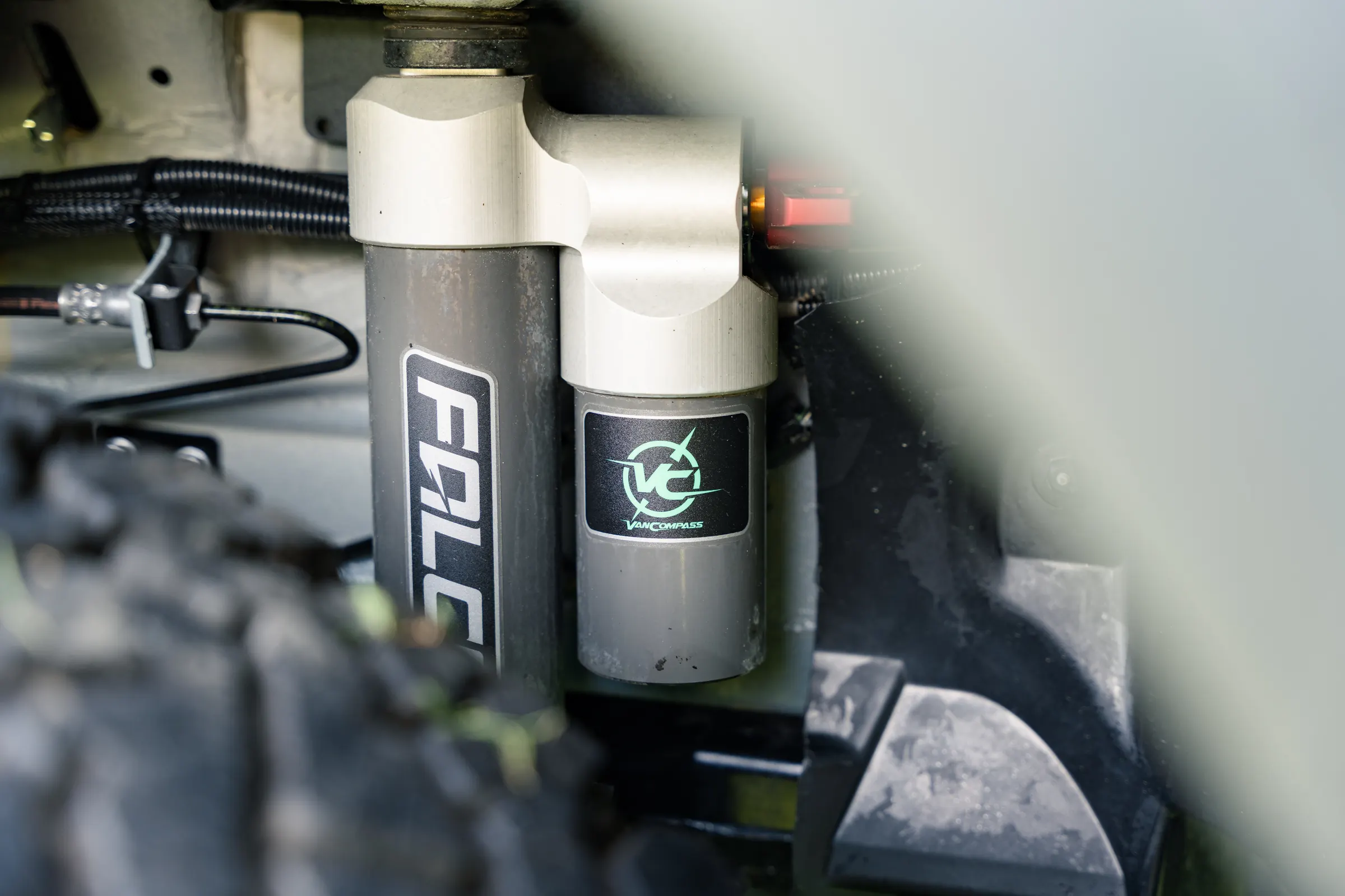 Close view of the front suspension, a Falcon shock absorber and its remote reservoir mounted behind the all-terrain tyre