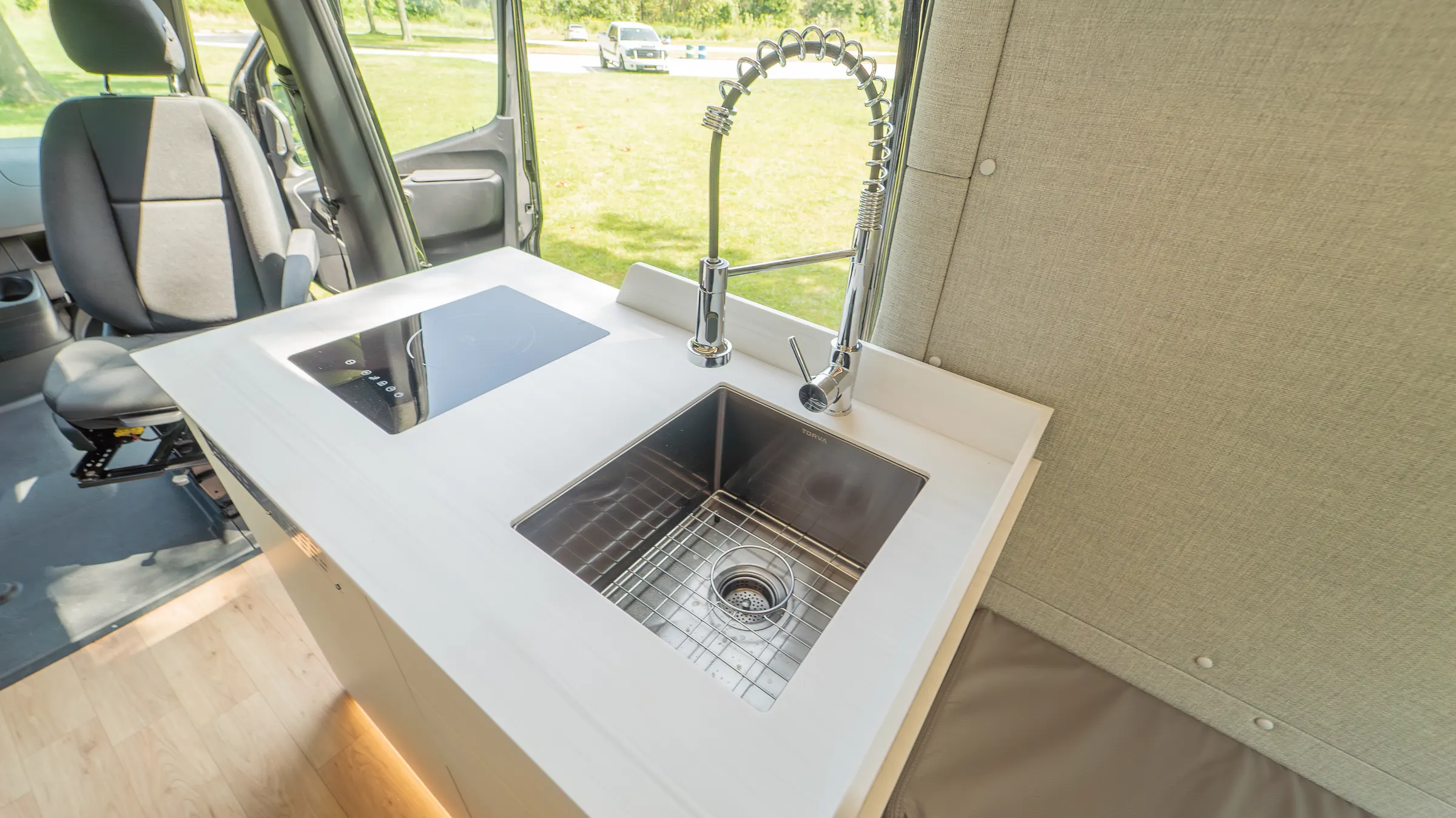 Undermount stainless sink with its bottom grid and a spring-neck faucet, set into the counter beside the induction cooktop