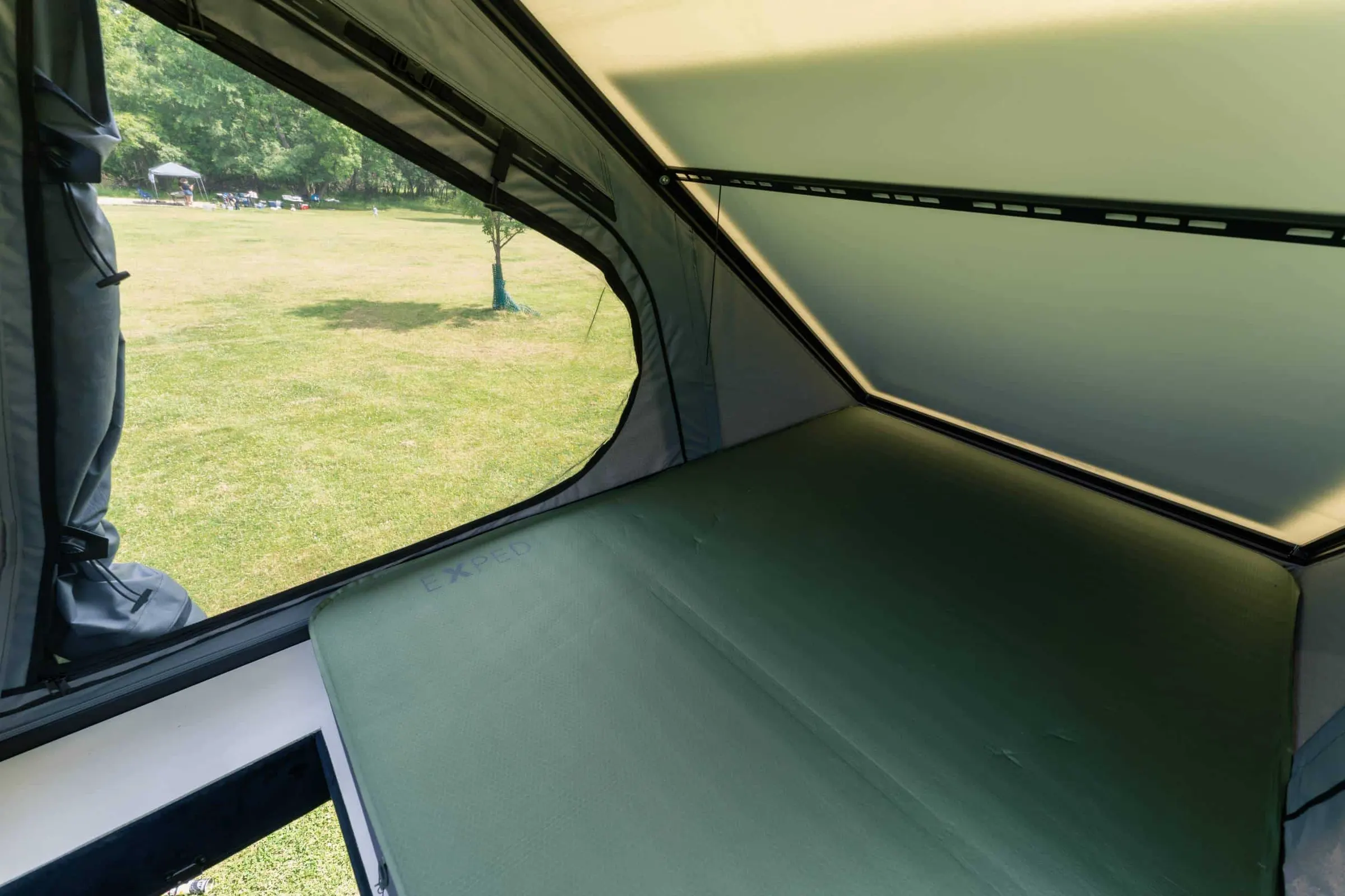 Inside the Parbat roof tent, looking out of the window onto grass