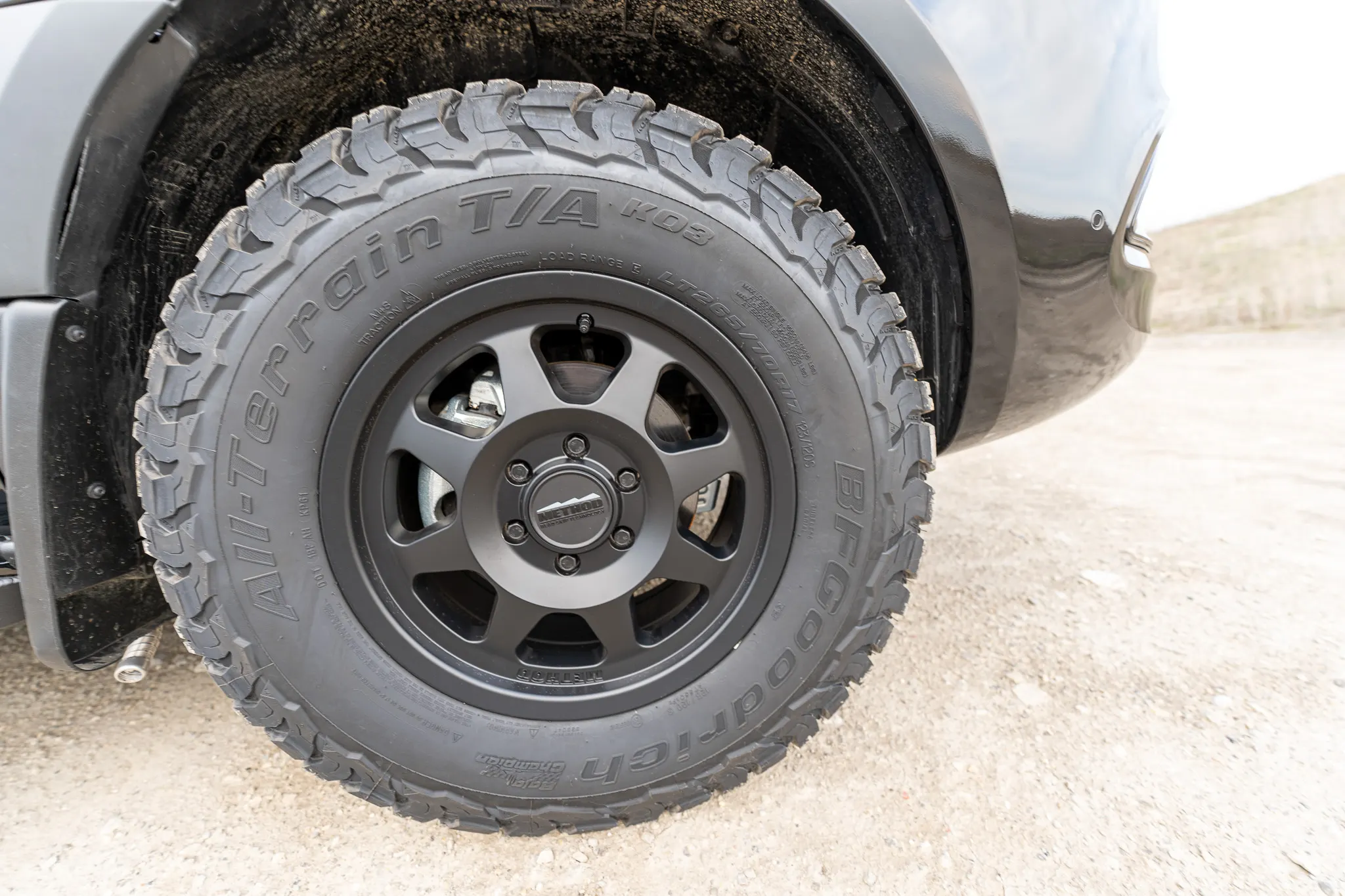 Close view of an all-terrain tyre on a grey seven-spoke wheel in the front arch