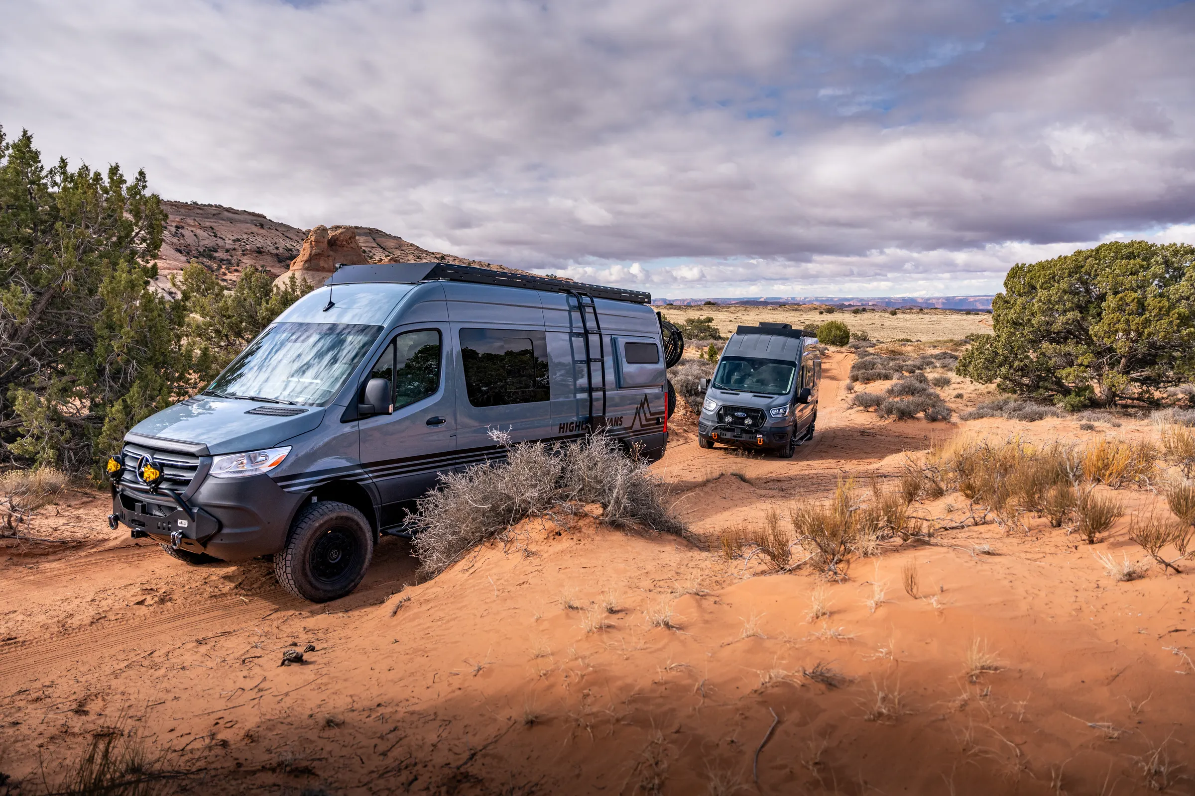 A Highland Vans Sprinter and a Ford Transit conversion on a red sand track in the desert