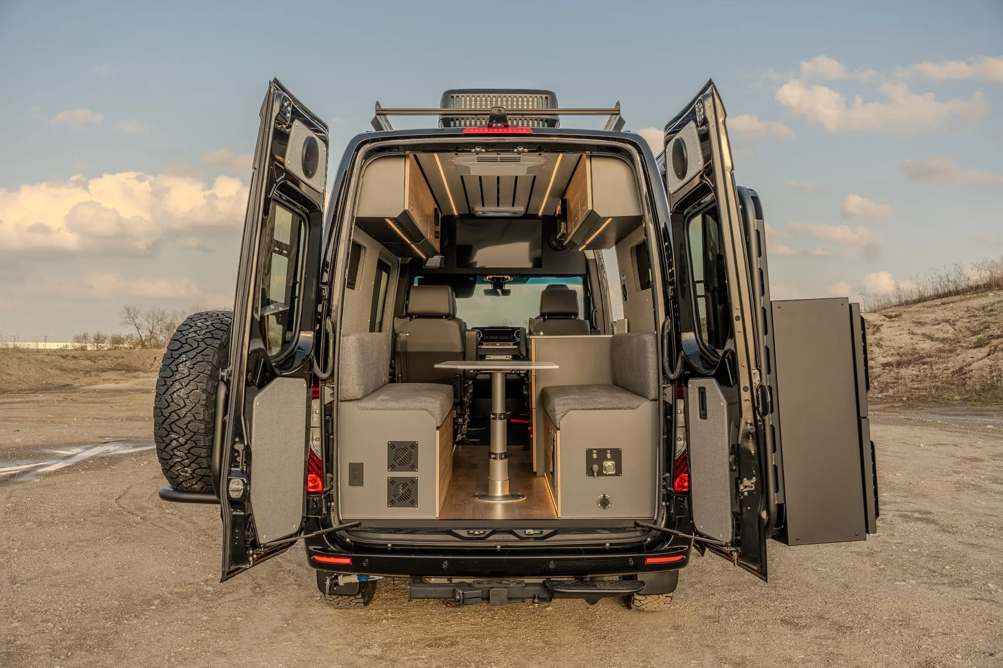 Luxury custom Mercedes Sprinter campervan interior featuring a cozy bed, full galley, and off-grid amenities