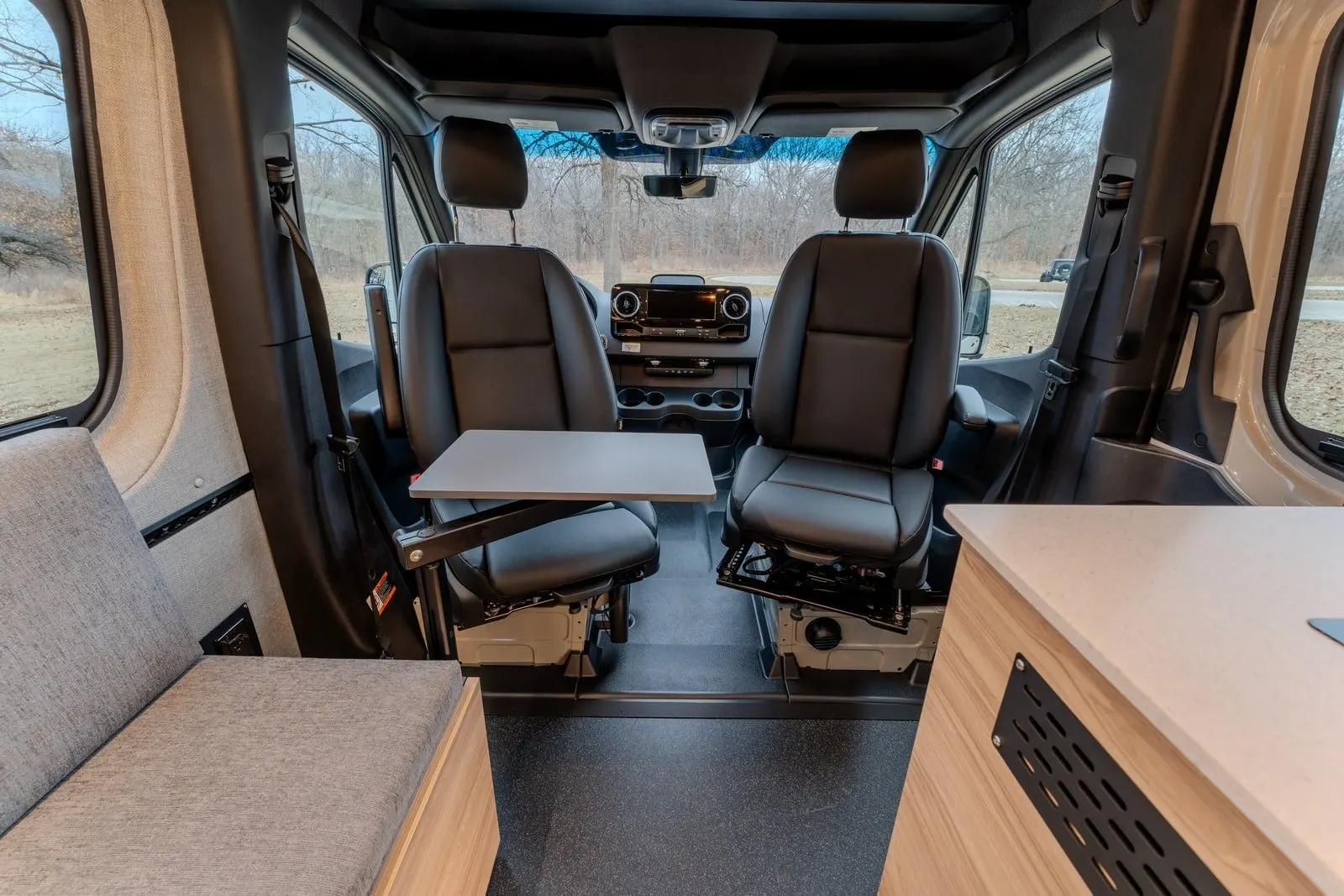 Aoraki cabin looking forward: two swivelled cab seats, a table between them and wood cabinetry