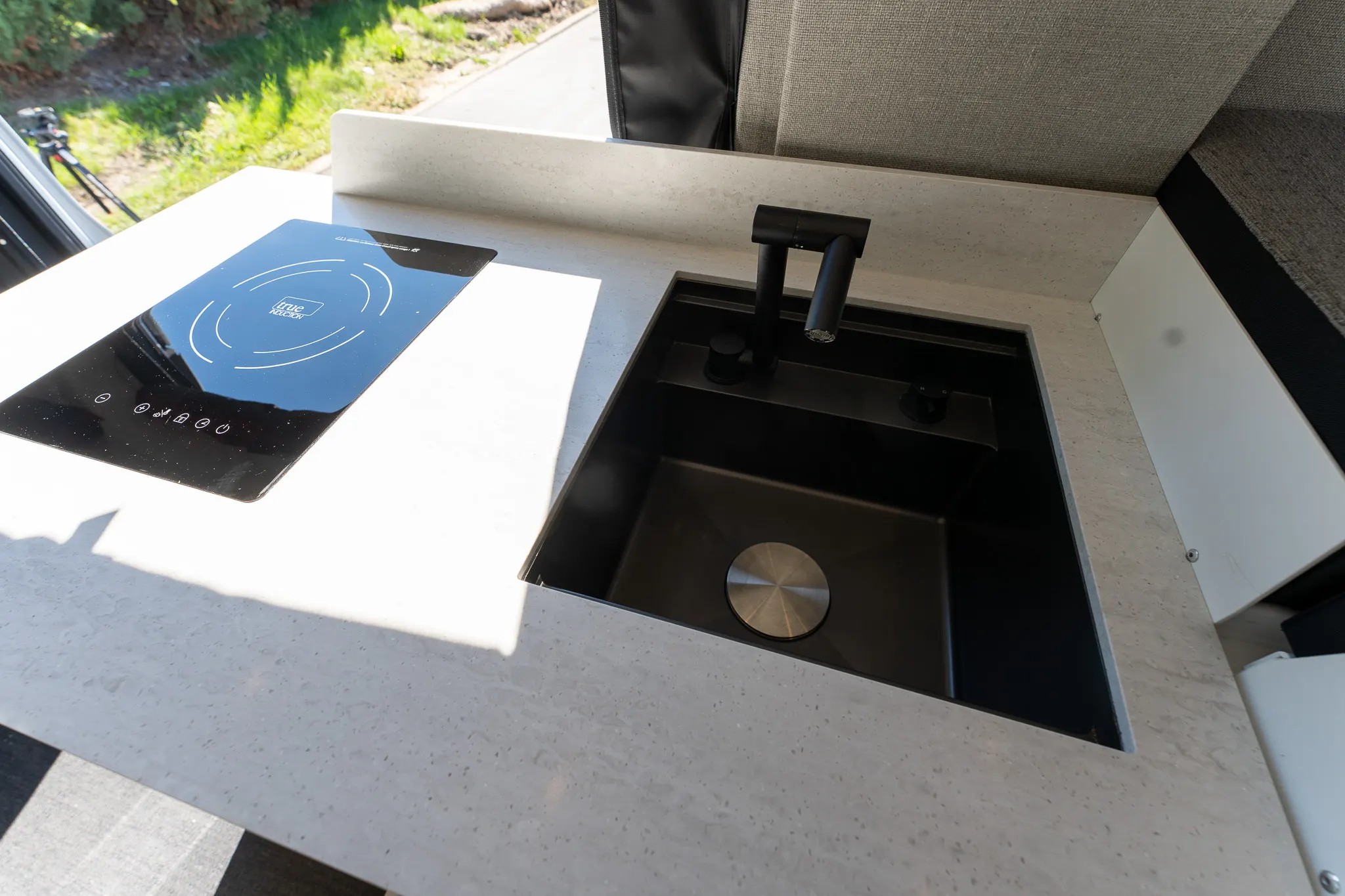 The induction cooktop and the deep black sink in the solid-surface counter