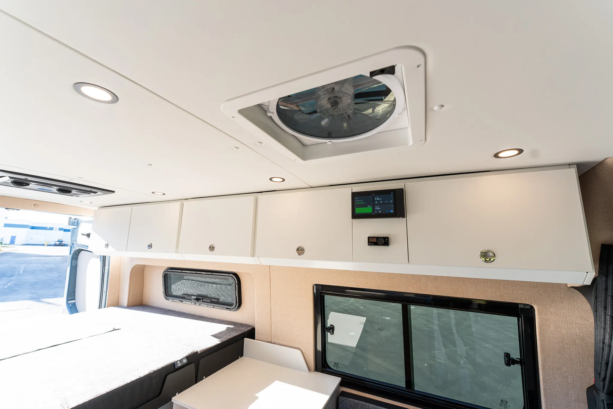 The bed made up sideways across the rear, under the roof fan and the overhead cabinets