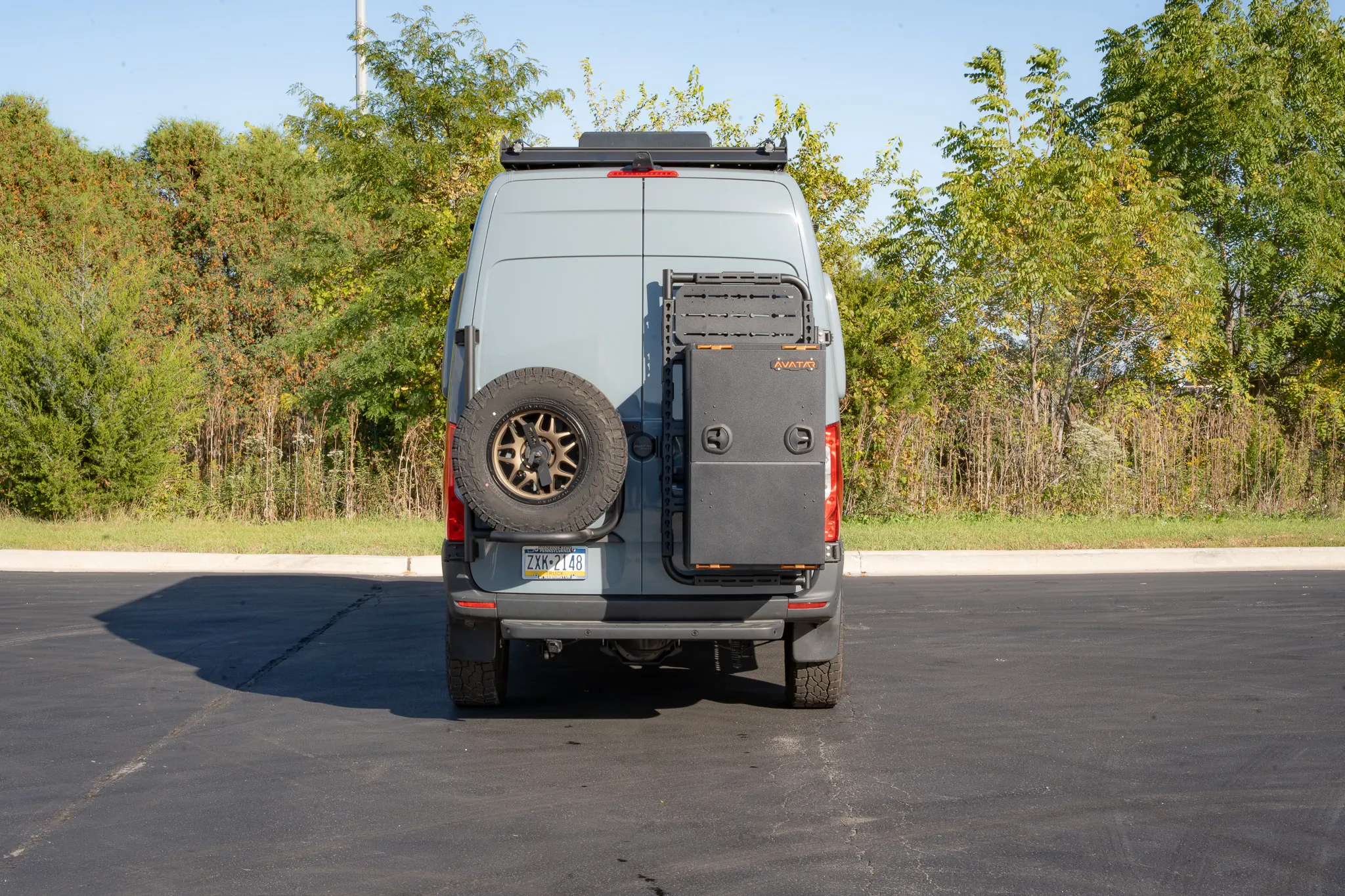 The rear, with the spare tire on one door and the storage box on the other