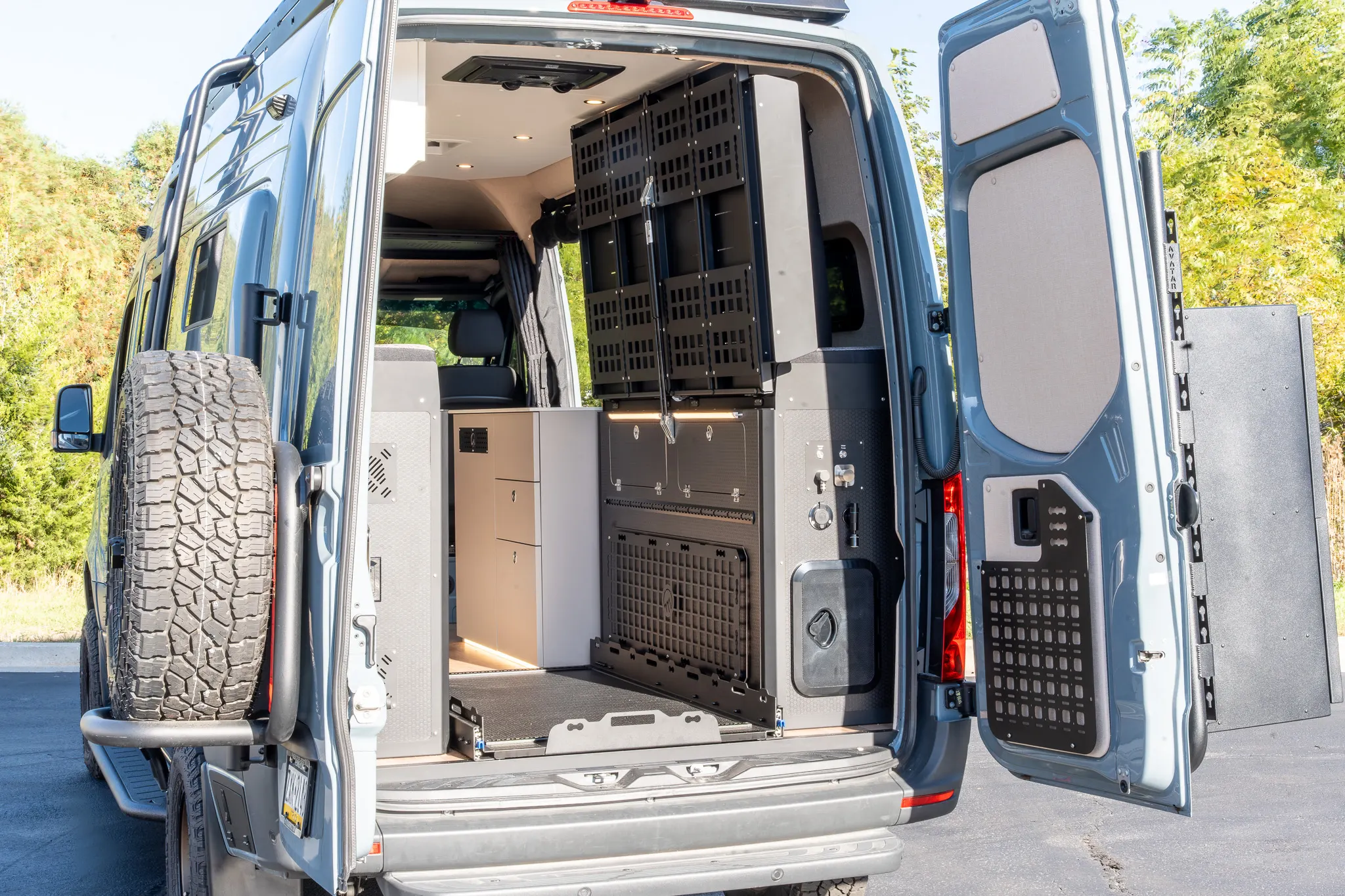 The rear doors open on the garage, with the bed folded up and the MOLLE panels