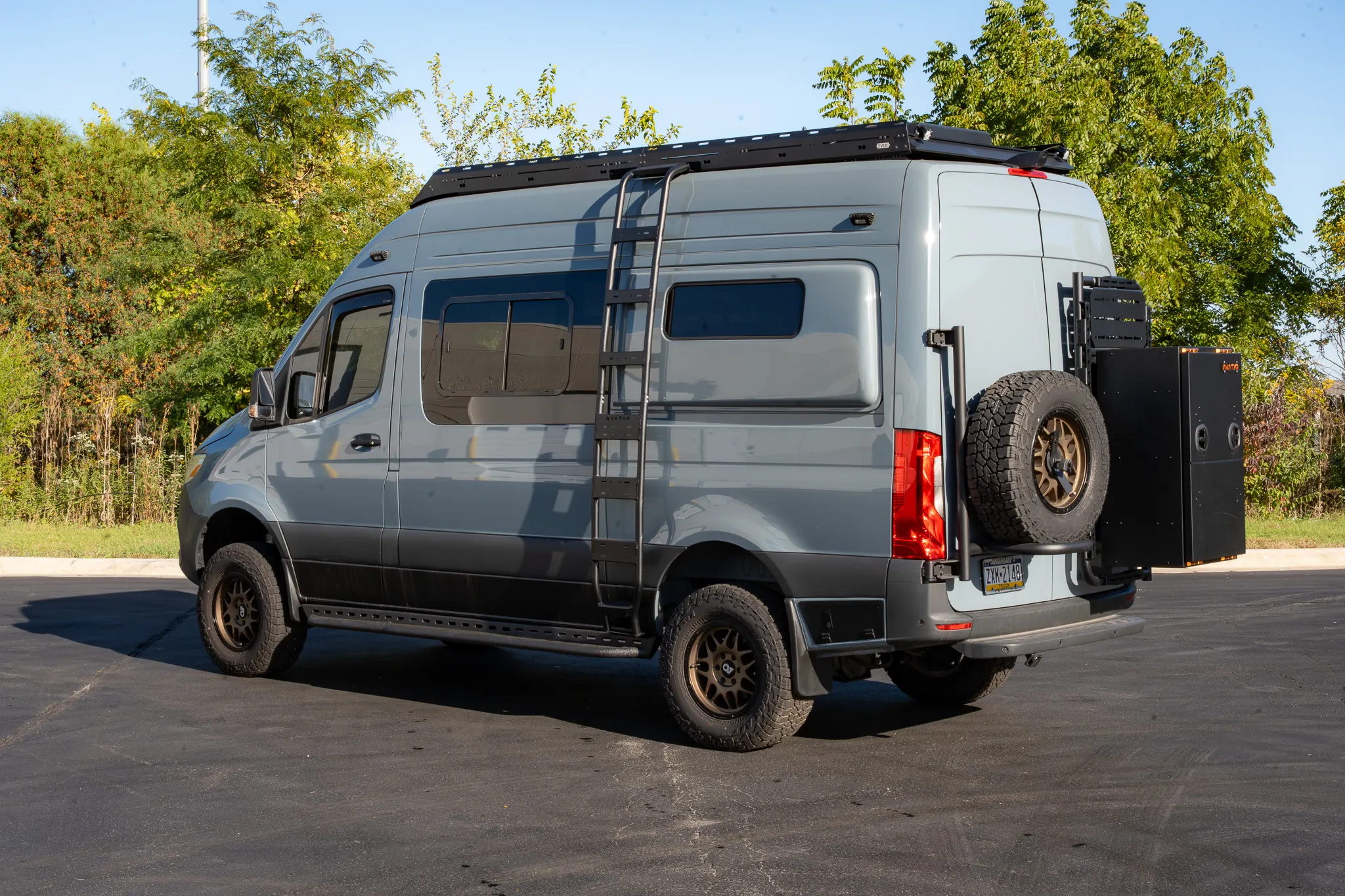The driver side, three-quarter view from the rear, with the ladder and the spare tire
