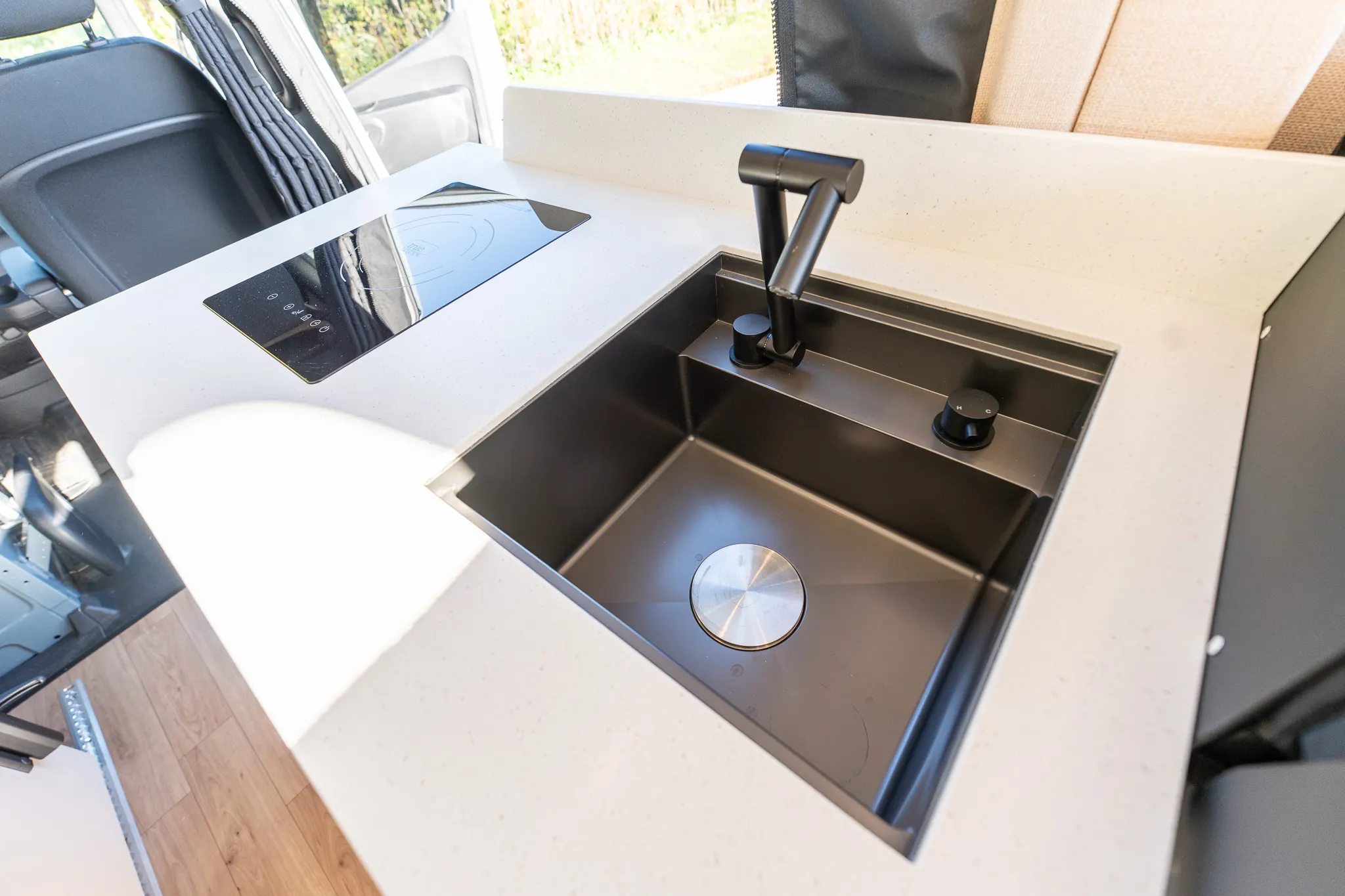 The induction cooktop and the deep black sink in the solid-surface counter