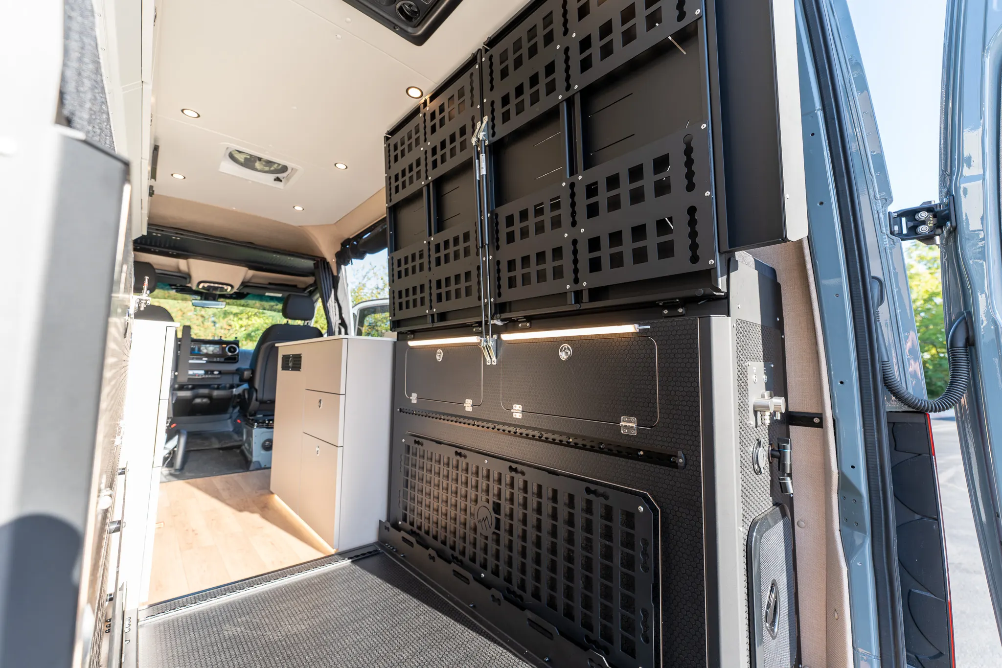 The Murphy bed folded up against the wall, with MOLLE panels on its underside