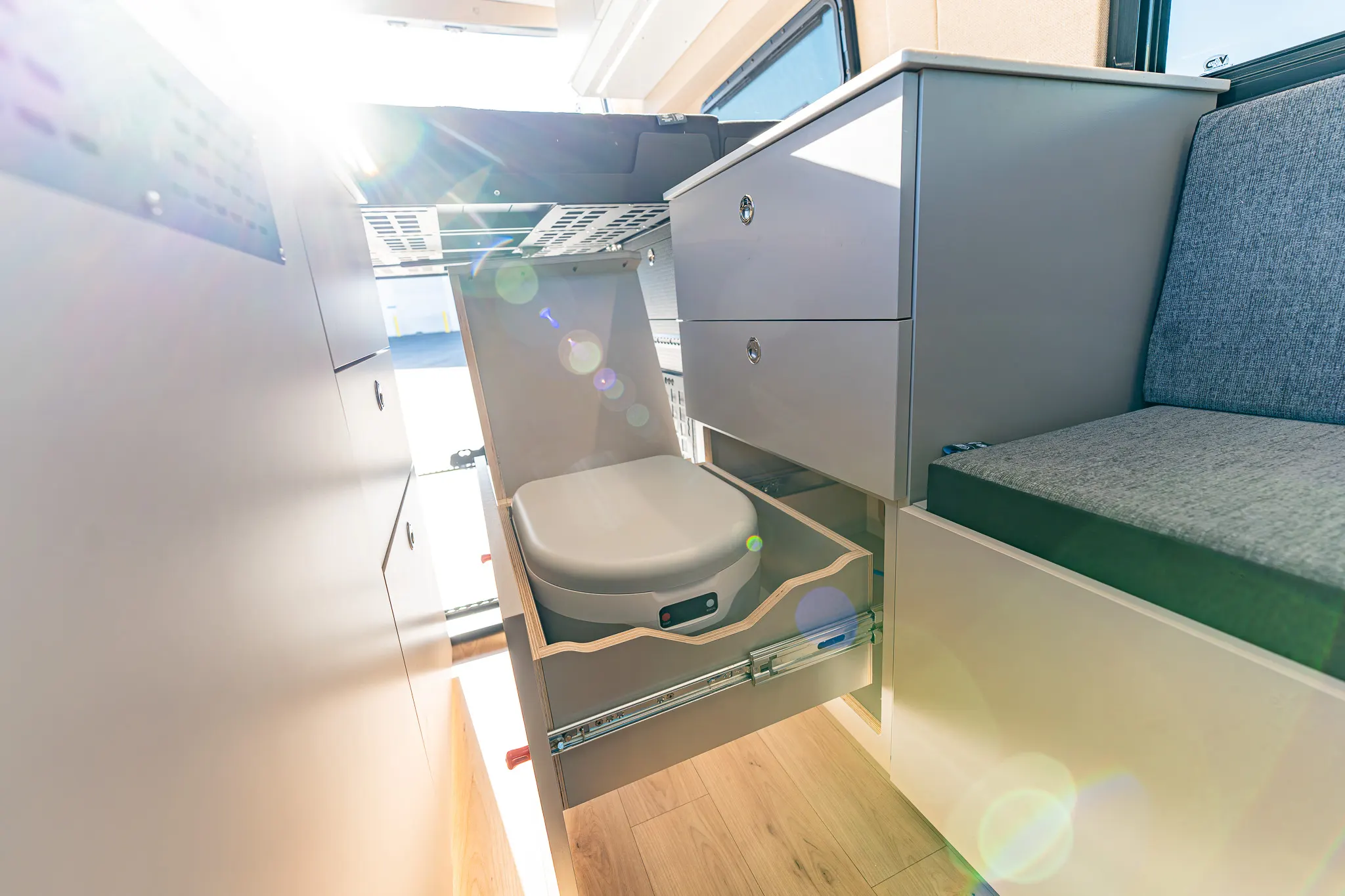 The toilet on its slide-out drawer in the secondary cabinet