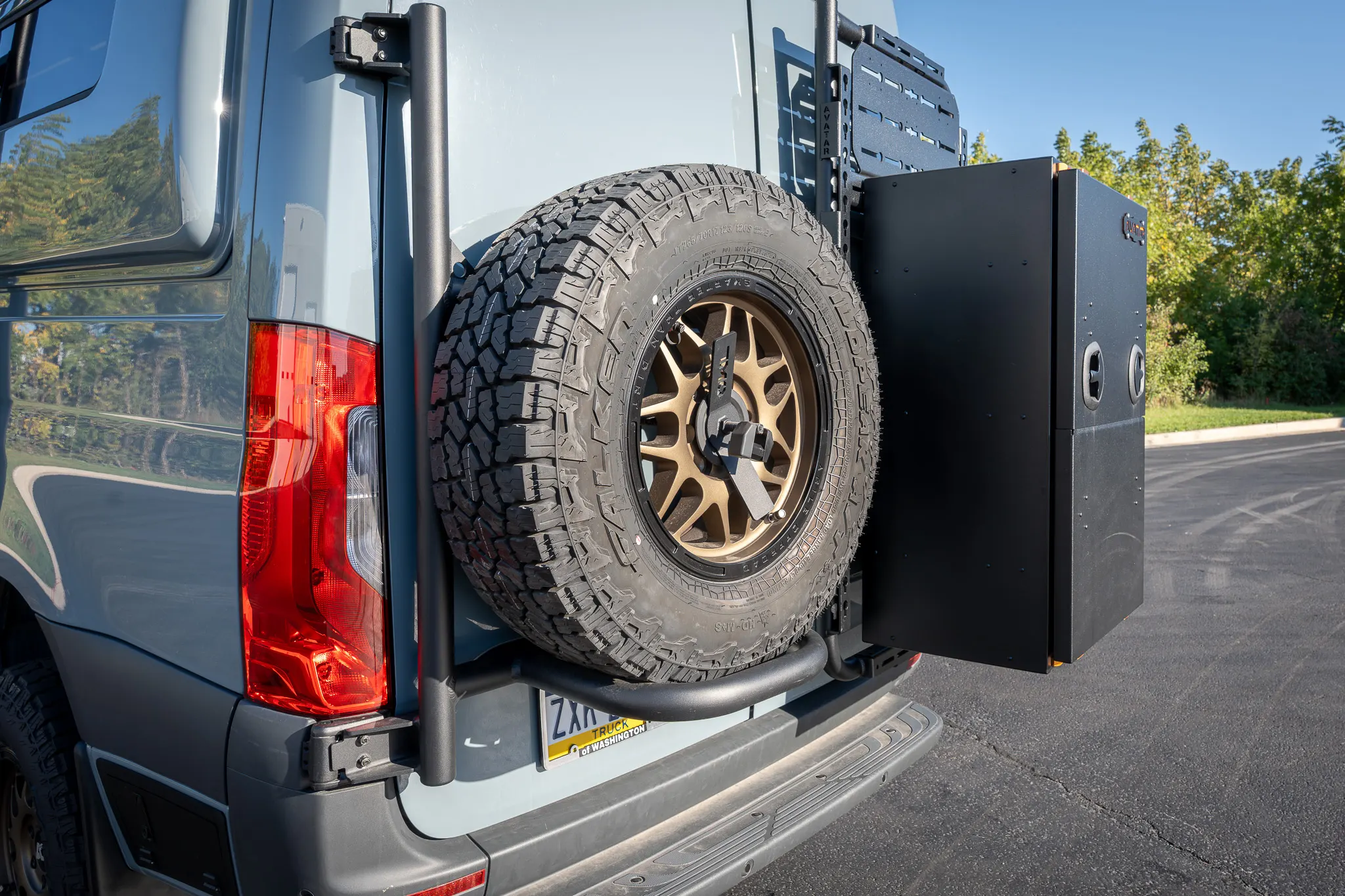 The spare tire on its carrier and the storage box, closed