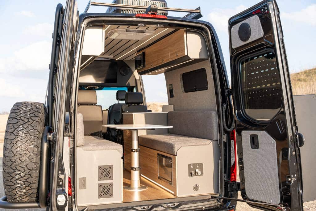 Luxury custom Mercedes Sprinter campervan interior featuring a cozy bed, full galley, and off-grid amenities
