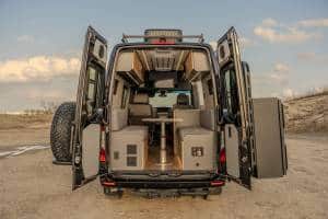 Luxury custom Mercedes Sprinter campervan interior featuring a cozy bed, full galley, and off-grid amenities